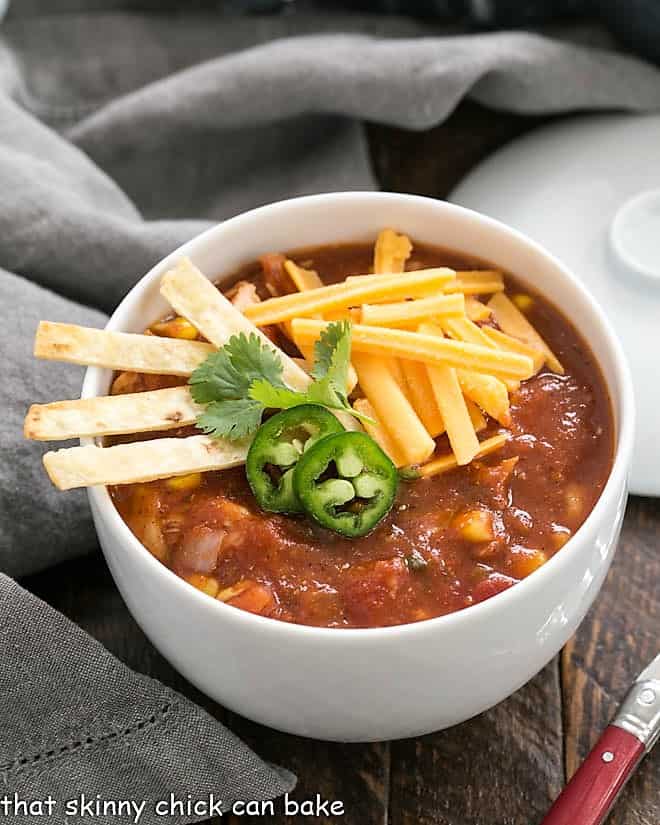Easy Chicken Tortilla Soup - helathy, hearty and full of flavor, this family friendly recipe is terrific for many occasions! Bowl of chicken tortilla soup garnished with cheese and jalapeno slices.