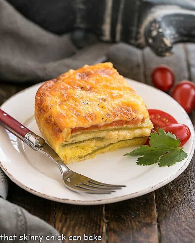 Low Carb Chili Relleno Casserole - Layers of gooey cheese, eggs, tomatoes and peppers make for an irresistible Tex-Mex dish! Chili Relleno Casserole slice on a round white place with a red handled fork.
