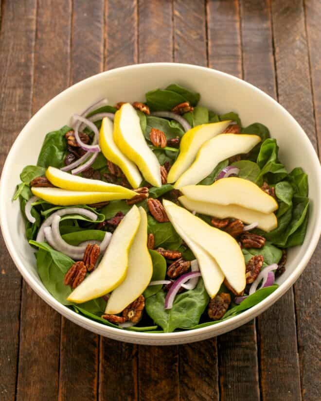 Overhead view of Spinach and Pear Salad in a serving bowl.