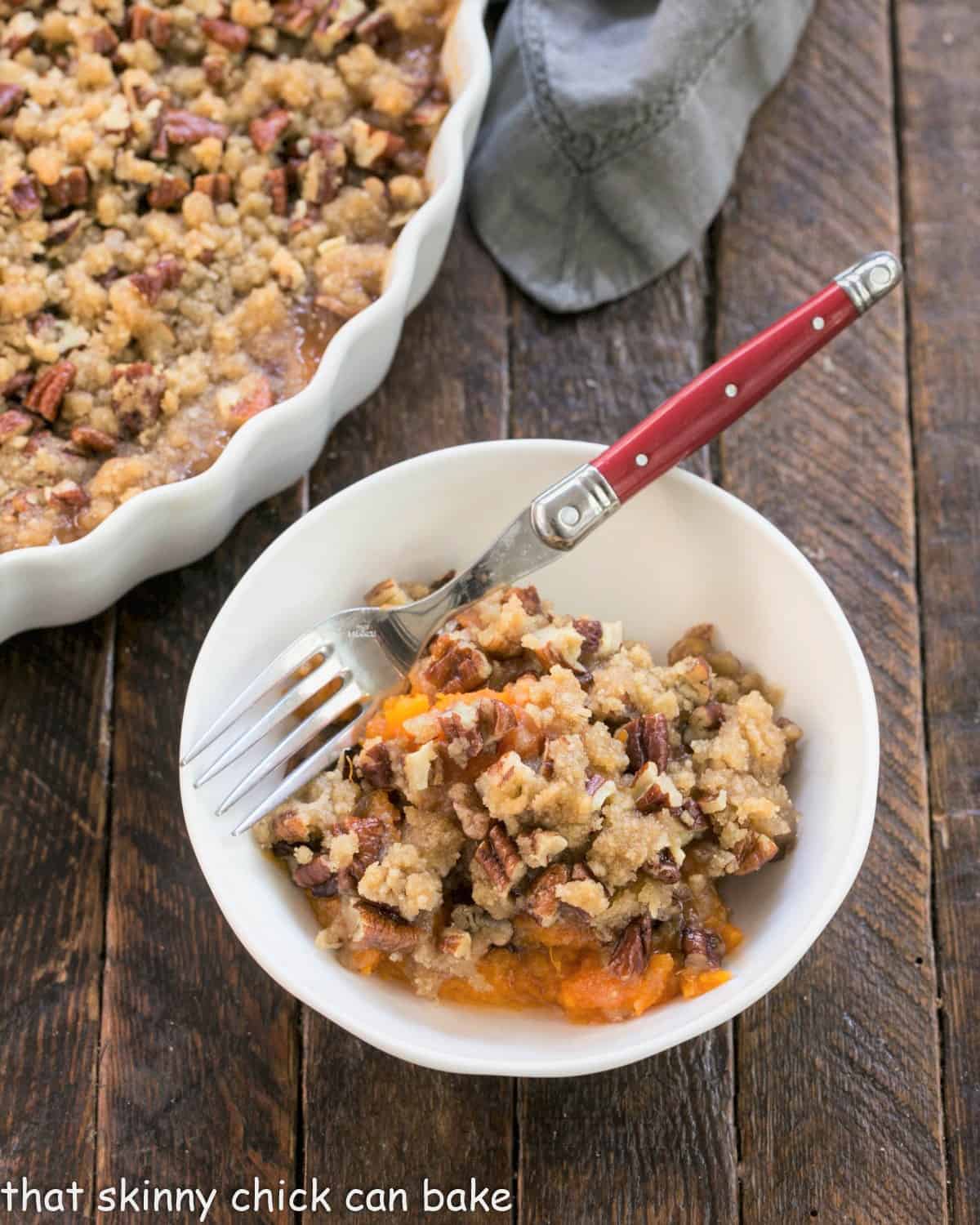 Small white bowl with easy sweet potato casserole and a red handle fork.