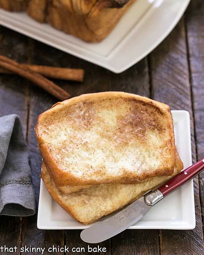Cinnamon Pull Apart Bread slices on a square white plate with a small knife.