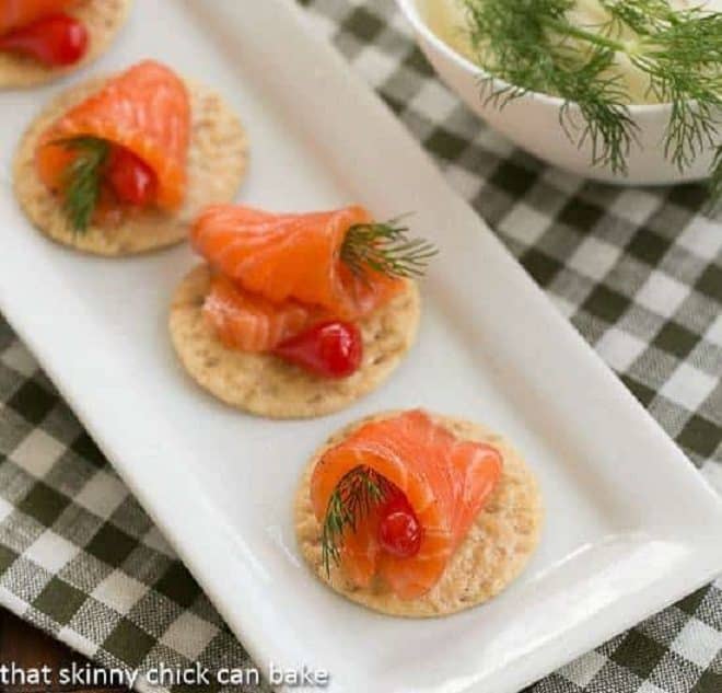 Dilled Gravlax with Mustard Sauce - a salt, sugar and dill cured salmon that's perfectly delectable! Dilled Gravlax on crackers on a white tray
