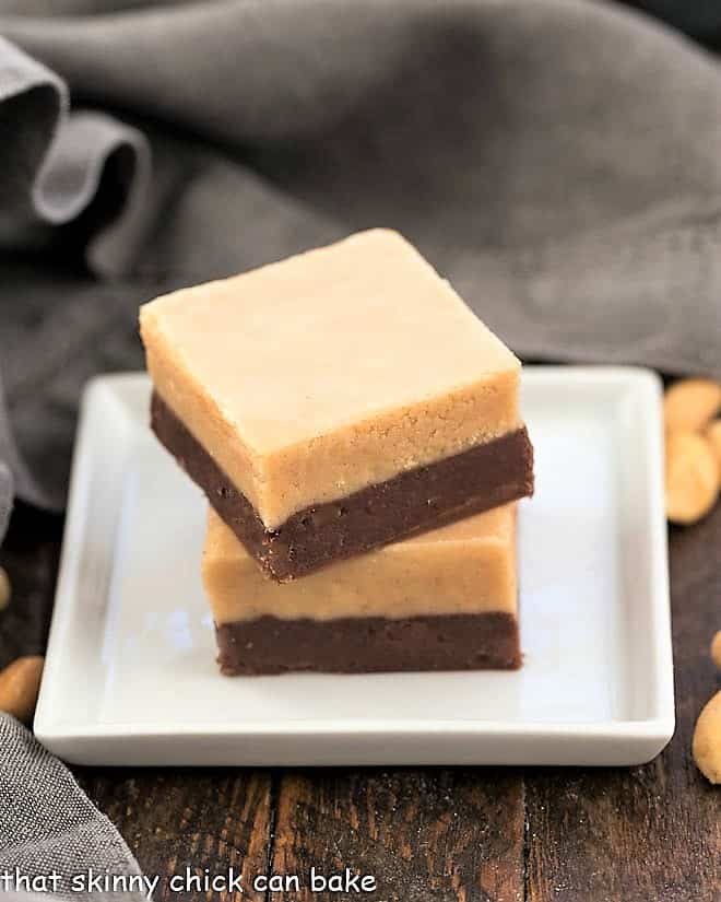 Two squares of peanut butter fudge on a square white plate.