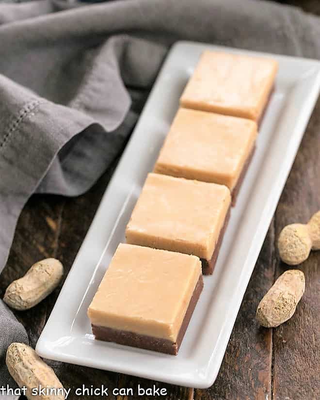 Layered Chocolate Peanut Butter Fudge squares on a white tray.