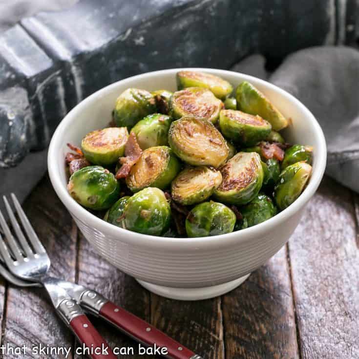 Pan brussels sprouts in a white bowl with 2 forks