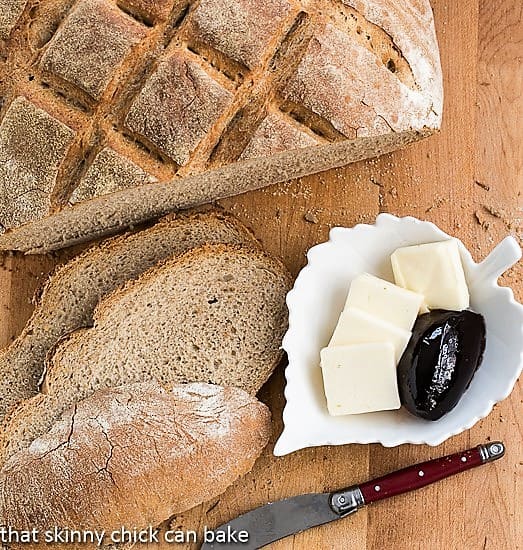 Country bread with a hearty crust sliced on a cutting board with butter and jelly