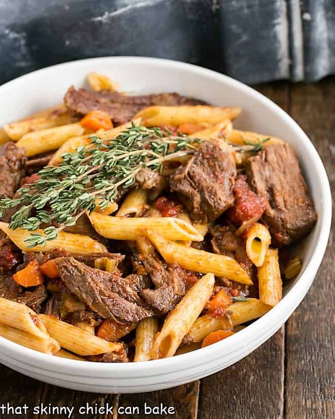 Beef Burgundy Pasta - a twist on the classic boeuf bourguignon in a pasta dish! Beef Ragu Pasta in a white serving bowl with a sprig of fresh thyme.