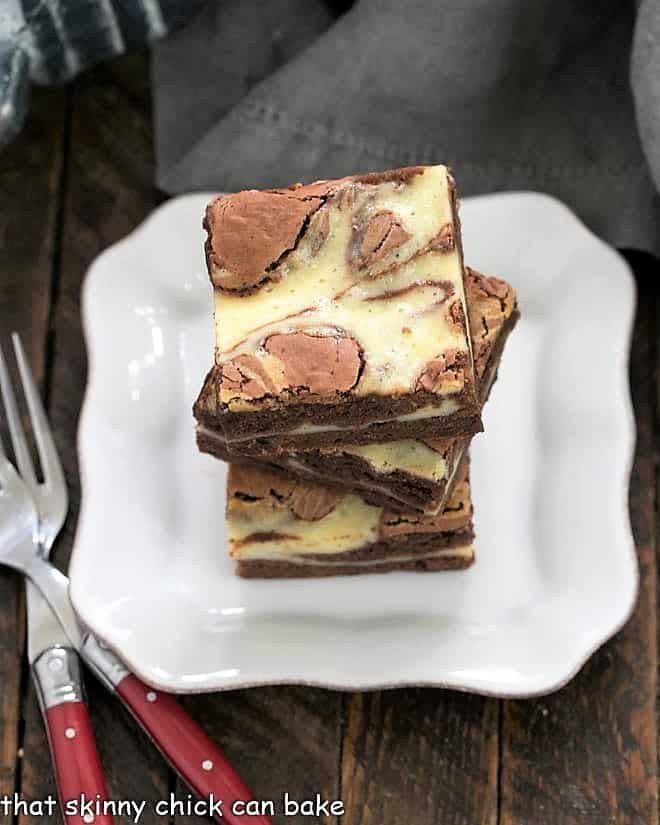 3 Cheesecake Swirl Brownies stacked on a small plate.
