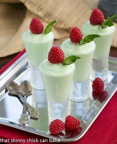 Grasshopper Mousse shooters garnished with raspberries on a silver tray.