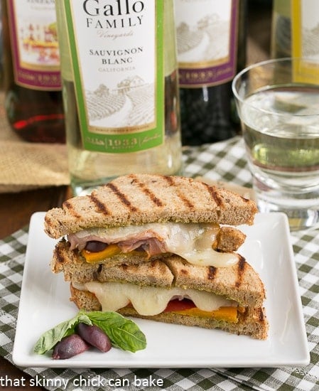 Sliced Mediterranean Grilled cheese on a square white plate with a basil and olive garnish