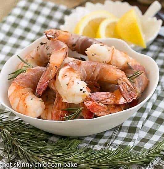 Rosemary Prosciutto Shrimp: Succulent, jumbo shrimp wrapped in prosciutto and flavored with rosemary and Sambuca! Rosemary Prosciutto Shrimp in a white bowl.