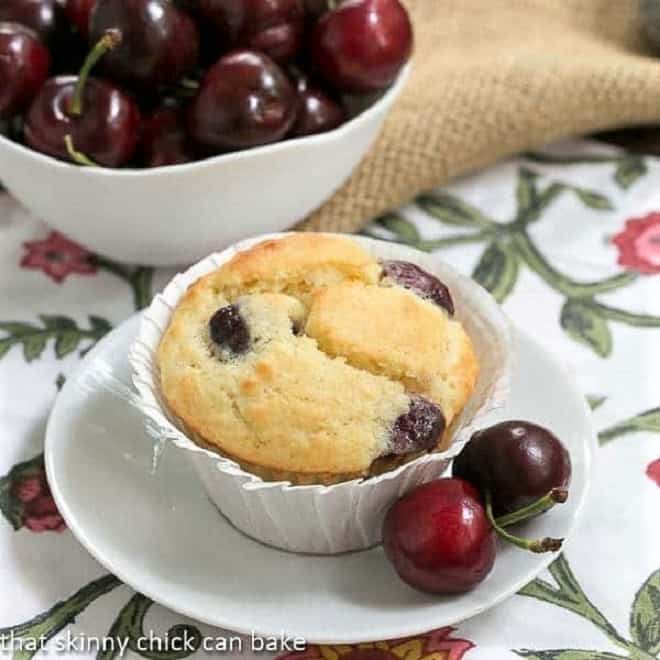 Double Cherry Muffins - Scrumptious, tender muffins with two kinds of cherries! Double Cherry Muffins on a white plate with fresh cherries.
