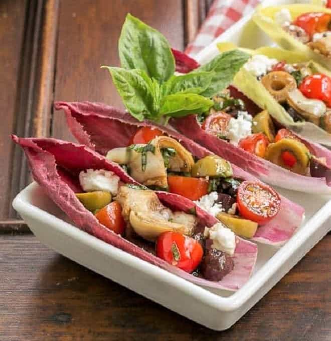 Mediterranean Endive Boats - a fun, bite sized salad or appetizer Close view of Mediterranean Endive Boats in a white, rimmed serving tray.