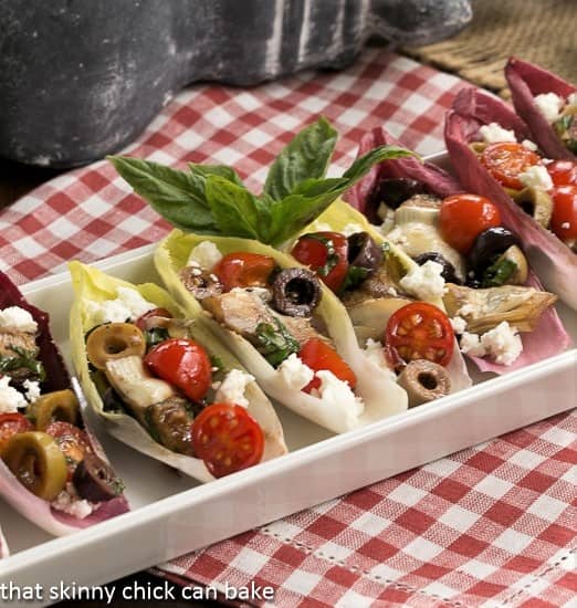 Mediterranean Endive Boats - a fun, bite sized salad or appetizer A white ceramic tray with endive leaves filled with salad.