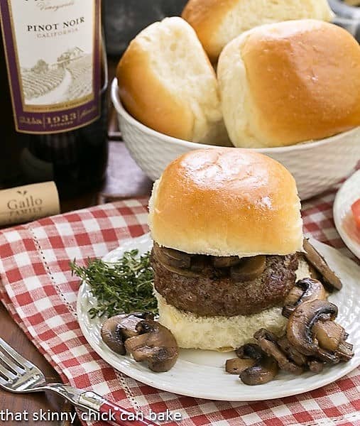 Mushroom Topped Pinot Noir Burgers on a white plate with mushrooms and herbs.