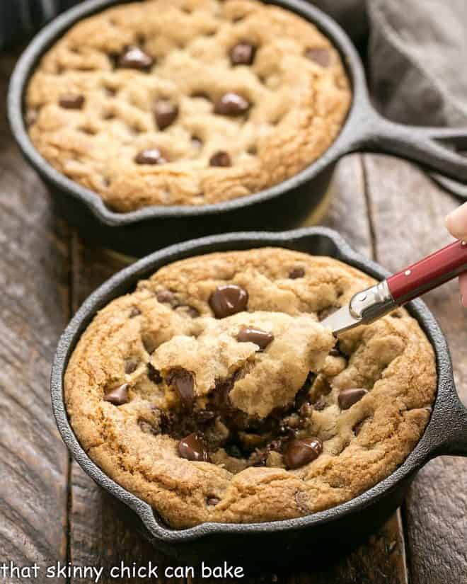 Two pizookies with a spoon removing a bite from the one up front