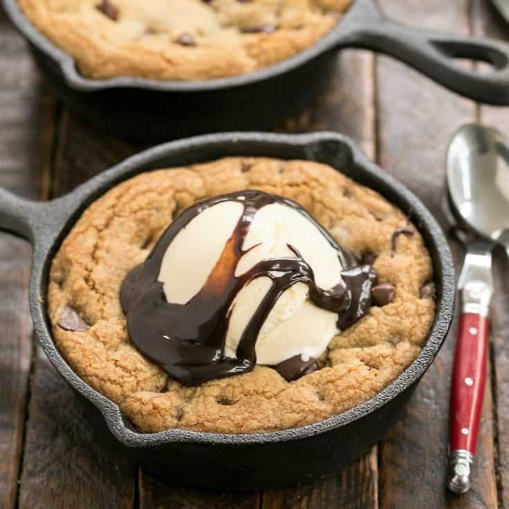 Overhead with of a pizookie topped with ice cream and fudge sauce with a red handle spoon
