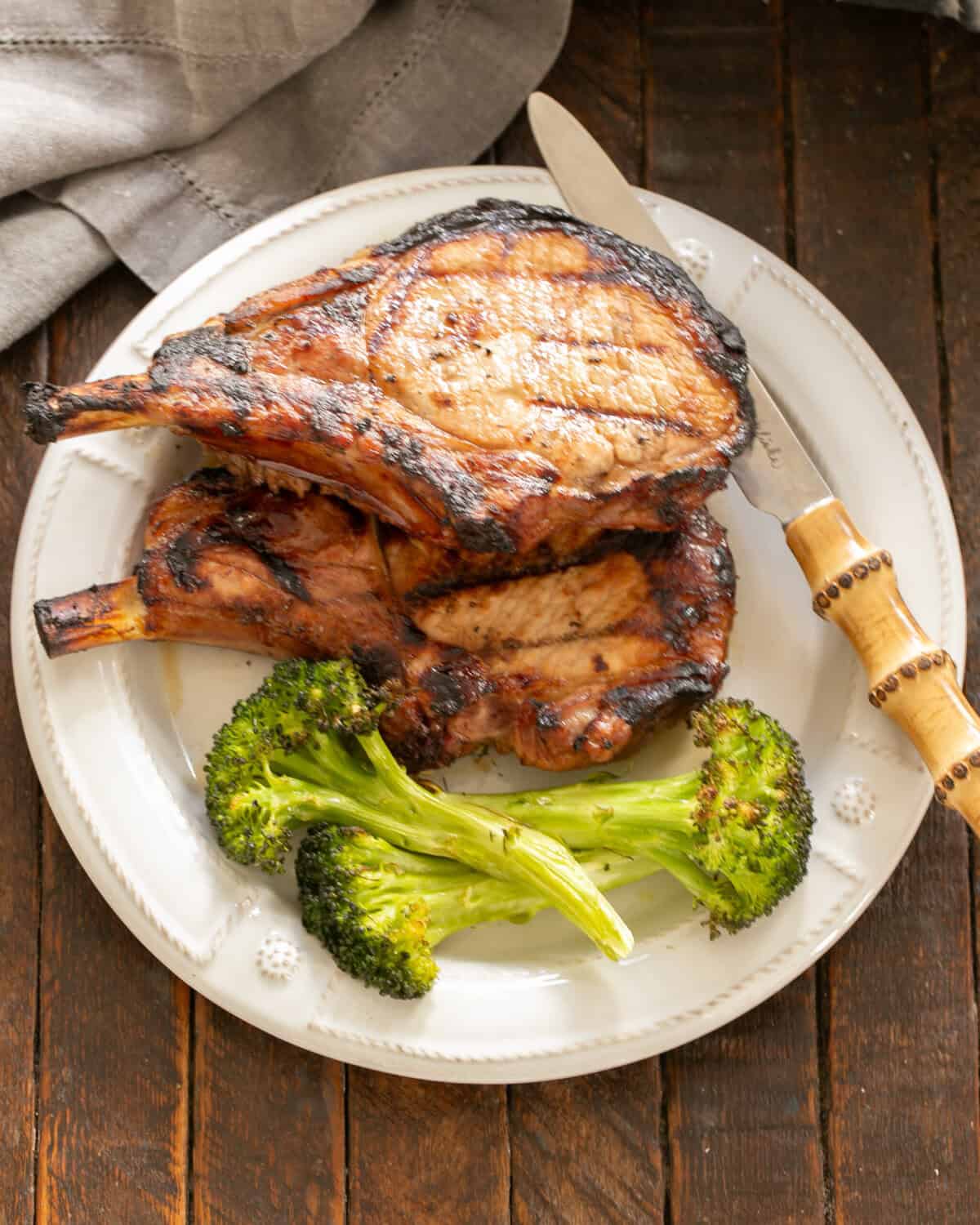 Grilled Pork chops on a white plate with broccoli.