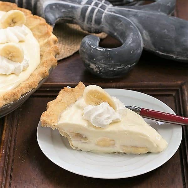 Slice of Banana Cream Cheesecake Pie on a white dessert plate.