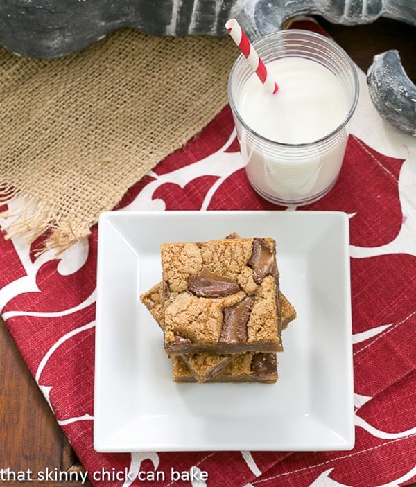 Biscoff Rolo Bars - Irresistible bars with Biscoff, Caramel and Chocolate! Biscoff Rolo Bars stacked on a square white plate with a glass of milk
