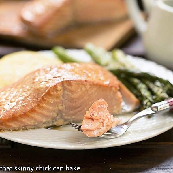 Plank grilling salmon with a simple marinade then grilled for an elegant tasty seafood entree! Grilled Cedar Plank Salmon on a plate i with a bite on a fork