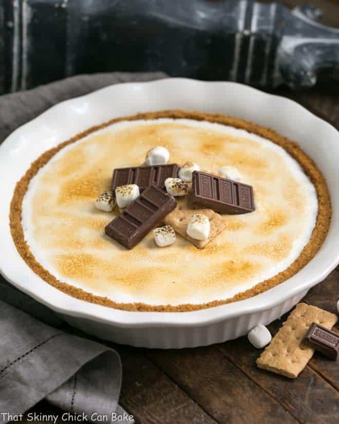 S'mores Pie topped with chocolate candy and mini marshmallows in a white pie plate.