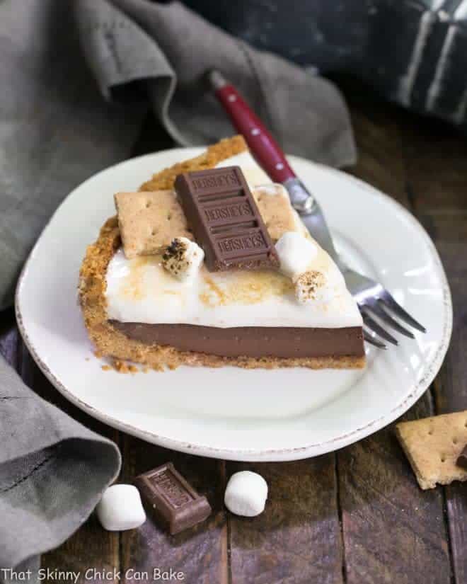 A slice of S'mores Pie on a dessert plate with a red handled fork.