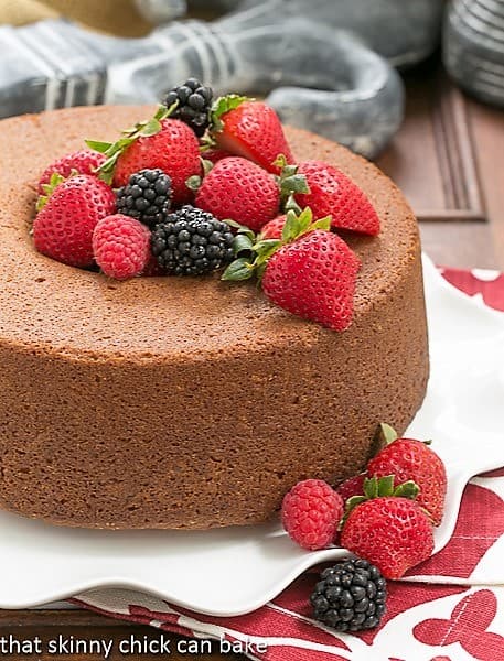 Vanilla Pound Cake - Perfect dessert topped with summer berries or any seasonal topping Whole Vanilla Pound Cake on a white ruffled plate topped with berries.