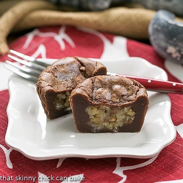 German Chocolate Brownie Cupcakes - cupcake sized brownies filled with gooey coconut filling German Chocolate Brownie Cupcakes cut in half on a white dessert plate with a red handled fork.