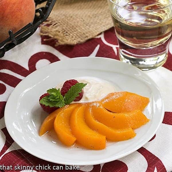 Poached peach fanned out on a white dessert plate.