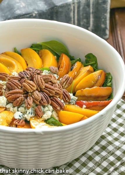 Spinach Salad with Grilled Peaches and Blue Cheese - a delicious summer salad using fresh, juicy peaches! Spinach Salad with Grilled Peaches and Blue Cheese in a white textured serving bowl