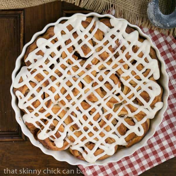 Overhead view of Apple Cinnamon Rolls drizzled with icing in a round ceramic dish.