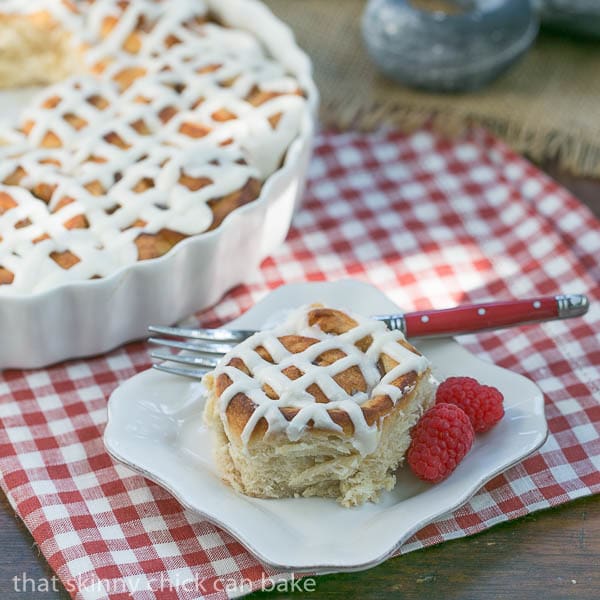 Apple Cinnamon Rolls in a baking dish and one on a small white plate with a red handled fork.