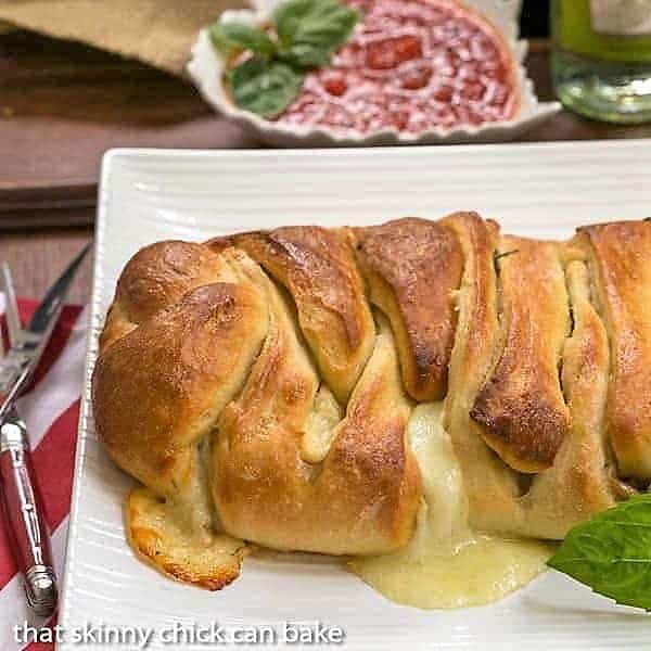Braided Stromboli - a perfect game day treat or Friday night dinner! Filled with meats and gooey cheese! Braided Stromboli on a white serving tray.