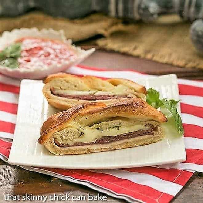 Braided Stromboli - pizza dough packed with Italian meats and cheeses Braided Stromboli on a square white plate with a sprig of basil.