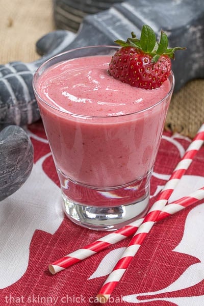 Berry Smoothies in a short glass with a berry garnish and two straws.