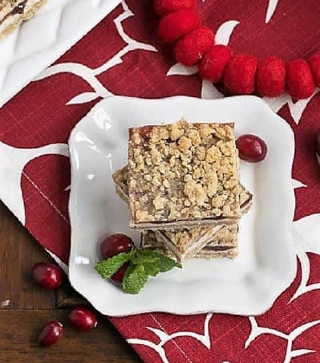 Cranberry Cheesecake Bars on a white dessert plate with fresh cranberries and mint.