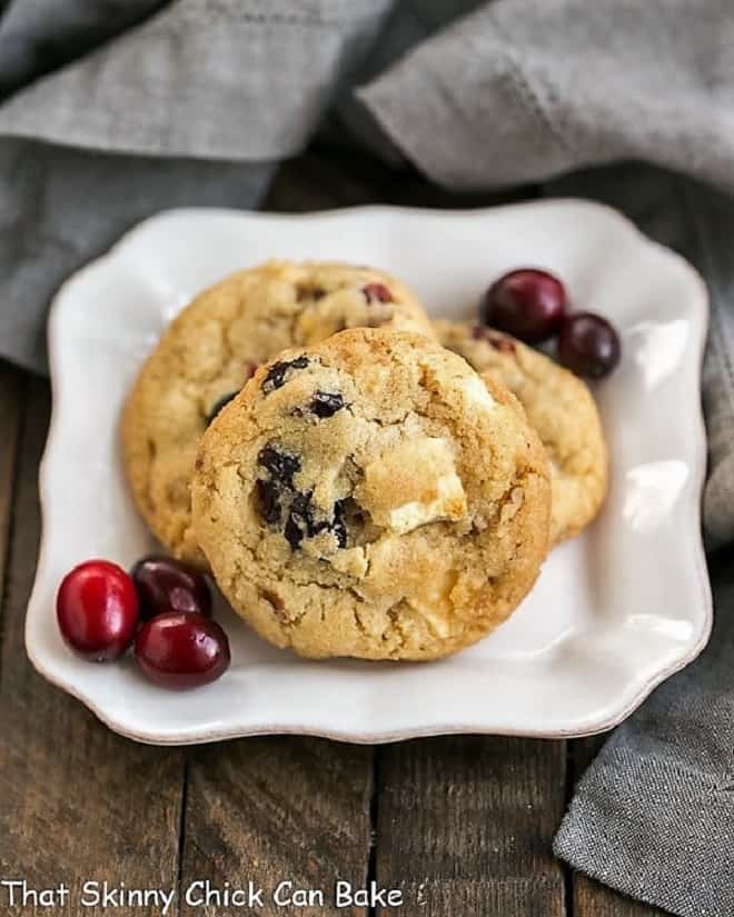 Cranberry, White Chocolate, Crystallized Ginger Cookies AKA Cranberry Bliss Cookies - A star studded cookie that's perfect for the holidays and all year long! Cranberry, White Chocolate, Crystallized Ginger Cookies on a square white plate with fresh cranberries.