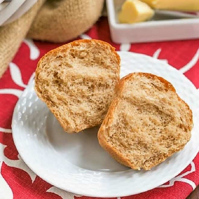  A Whole Wheat Dinner Roll on a white plate, split open.