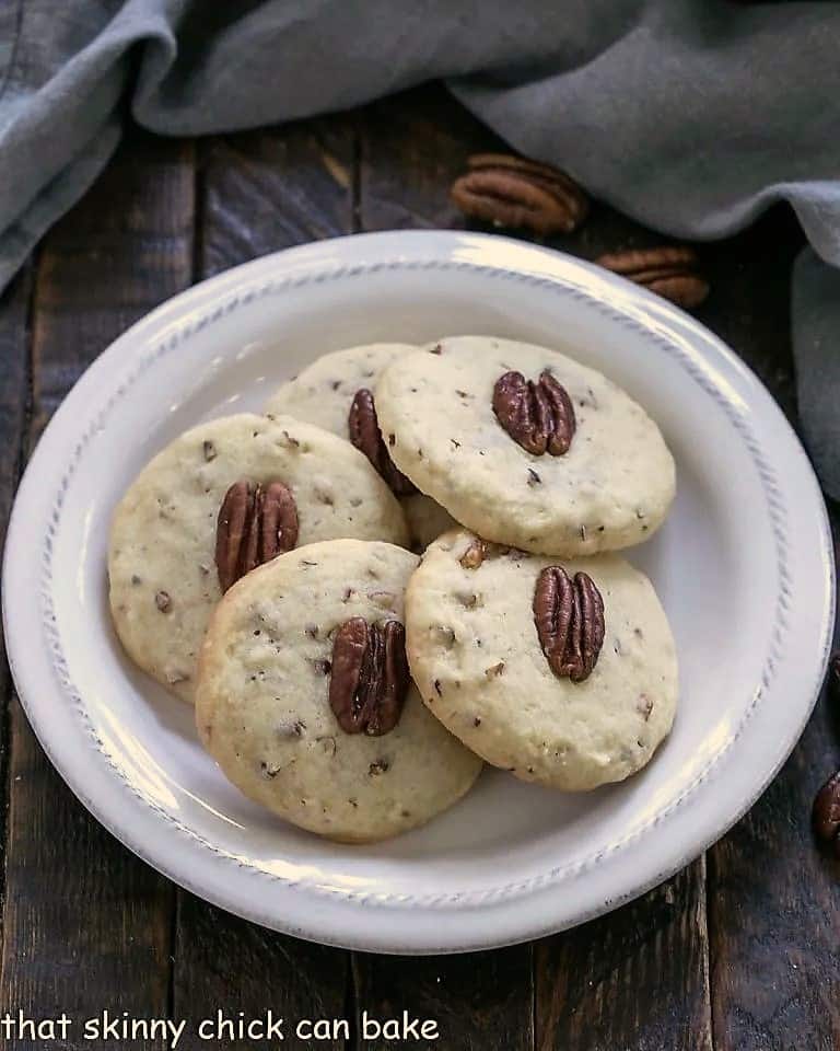 4 pecan sandies cookies on a round white plate.