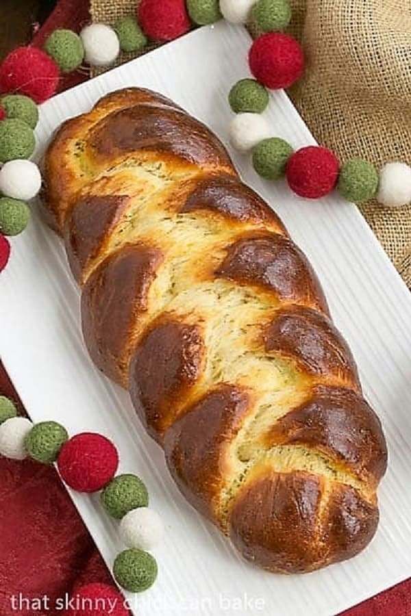 Swiss butter braid is a slightly sweet, plaited, special occasion bread, perfect for the holidays, entertaining or for a special treat. Crank up your oven a bake a loaf of this magnificent Swiss butter braided bread recipe, also known as Butterzopf. #bread #recipe #holidaybaking overhead view of a beautiful loaf of Swiss Butter Braid (Butterzopf) on a white platter.