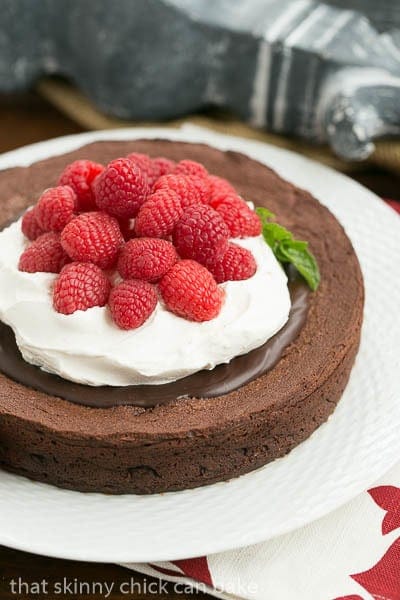 Chocolate Earthquake Cake - a dense chocolate souffle cake that is supposed to rise and fall!! Chocolate Earthquake Cake on a white cake plate with a mint garnish.