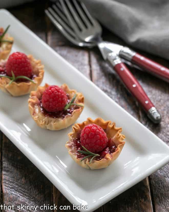 Baked Brie appetizers on a white serving tray.