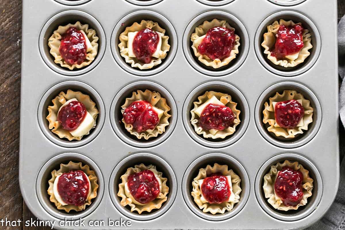 Unbaked Brie appetizers in a muffin tin.