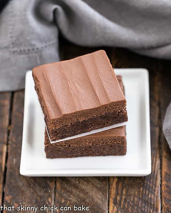 Frosted Brownies Recipe - Fudgy brownies topped with rich, chocolate buttercream frosting Frosted Brownies Recipe stacked on a small white plate.