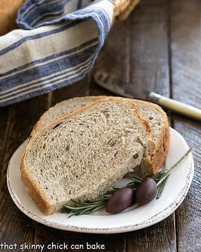 Rosemary Olive Bread slices on a white plate with fresh rosemary and olives