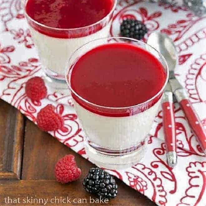 Vanilla Bean Panna Cotta Recipe - topped with a raspberry sauce or berries for an elegant Italian dessert Vanilla Bean Panna Cotta in glasses on a red and white patterned napkin with fresh berries