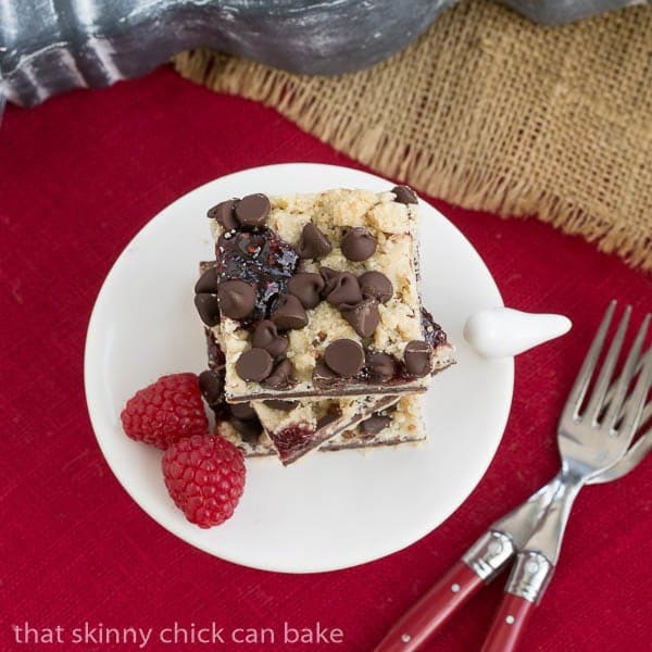 Overhead Chocolate Raspberry Crumb Bars on a white pedestal on a red napkin.