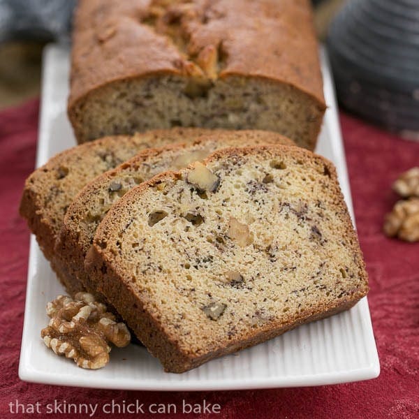 A loaf of banana nut bread and slices on a white tray.
