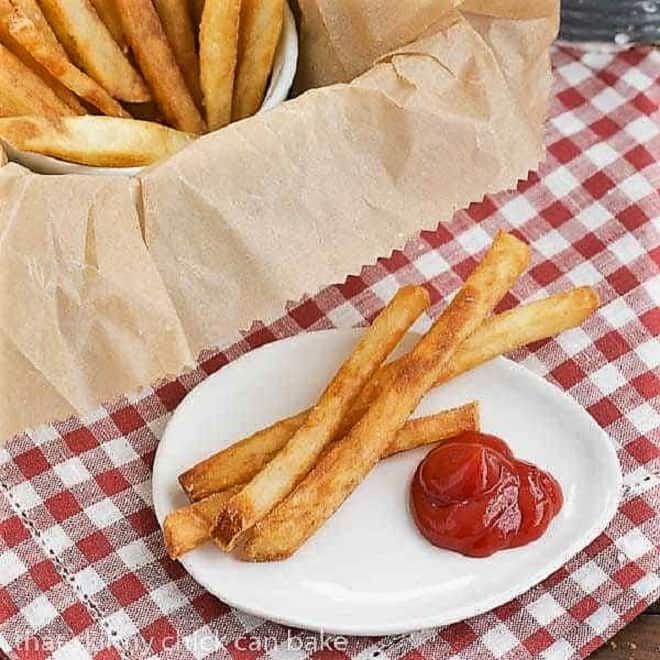 Thin Crispy French Fries on a white plate with a dollop of ketchup.